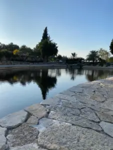 בריכה שלווה המשקפת את השמים הכחולים והצלולים, מוקפת שבילי אבן ועצים שופעים, משרה אווירה שלווה למטיילים בישראל. היופי הטבעי שלה הוא אחד מהאטרקציות שחובה לראות עבור כל בלוג טיולים בארץ.